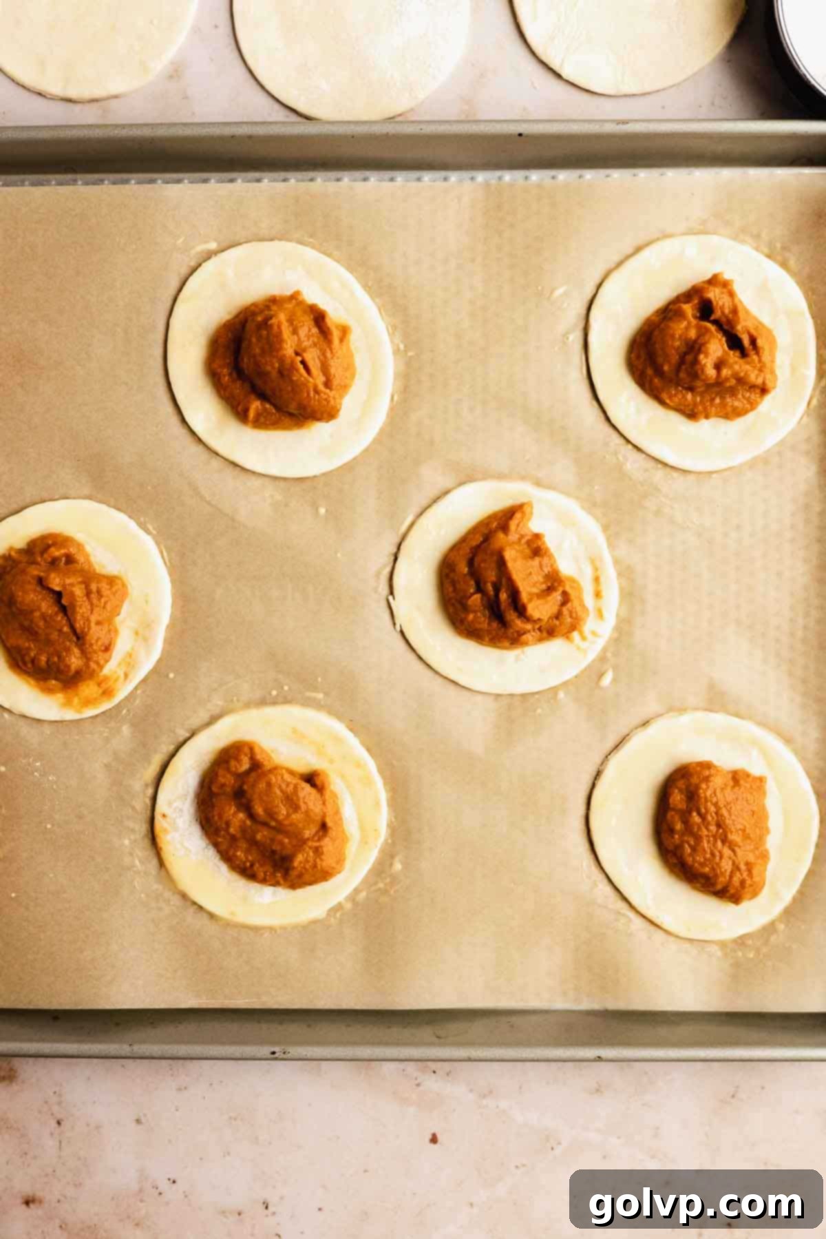 Placing portions of pumpkin filling onto round pastry circles.