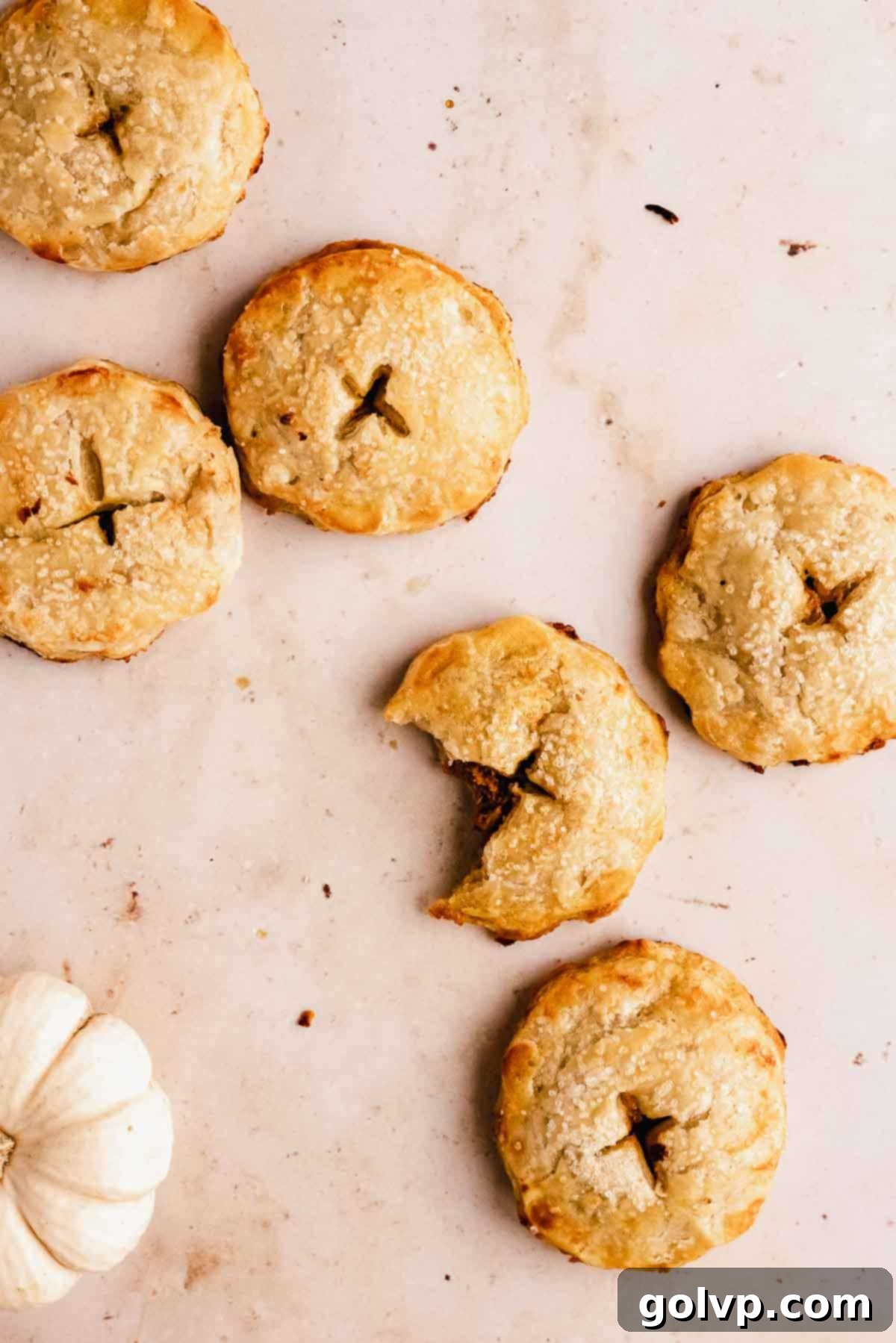 Baked mini pumpkin hand pies on a marble slab, showing their golden color and crisp texture.