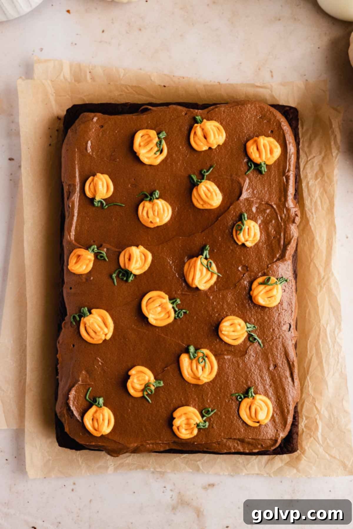 Sheet cake beautifully decorated with numerous piped mini orange pumpkins and green stems, creating a festive fall design