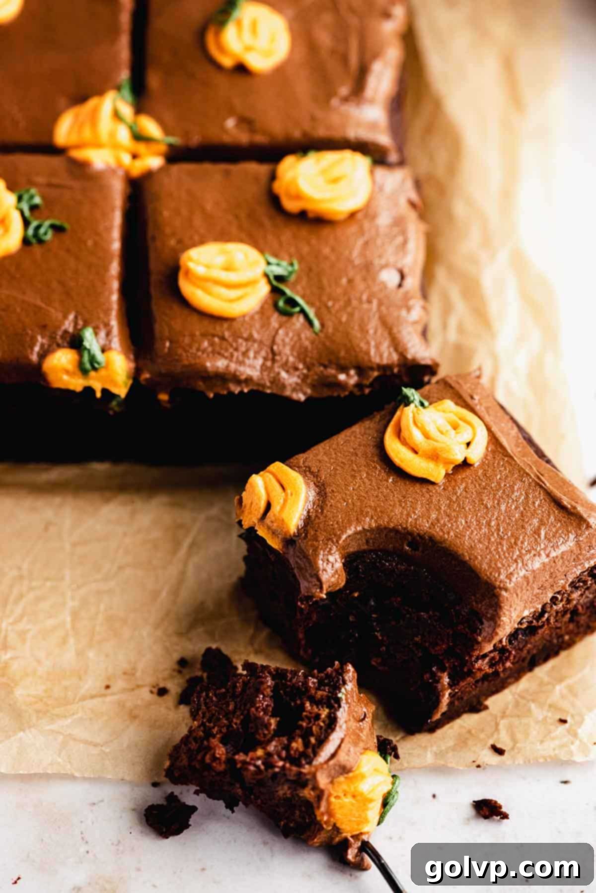Close-up of a hand taking a bite of a slice of moist pumpkin chocolate cake with creamy frosting