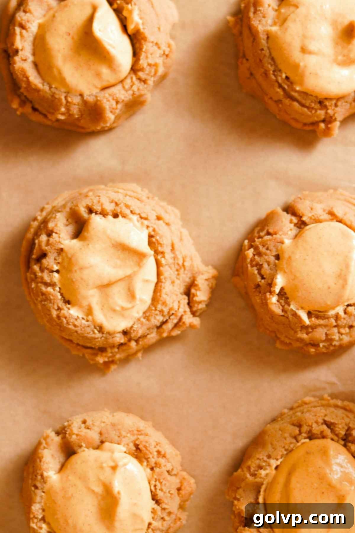 Decadent Pumpkin Cheesecake Cookies 10 unbaked cookie dough balls on parchment paper with pumpkin filling inside