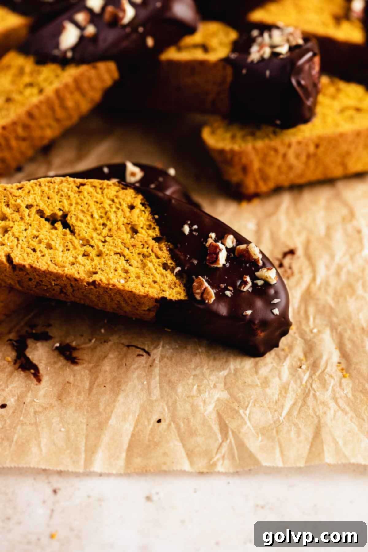Autumn Pumpkin Biscotti 12 A stack of chocolate-dipped pumpkin biscotti resting on a wooden surface, highlighting the rich chocolate coating and warm spiced interior.