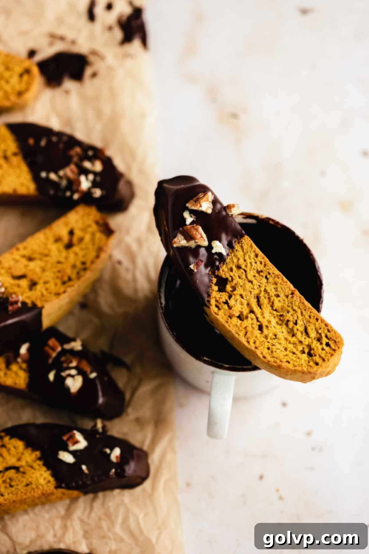 Autumn Pumpkin Biscotti 3 Two pumpkin spice biscotti elegantly placed on the rim of a ceramic mug, suggesting a perfect pairing with a warm beverage.