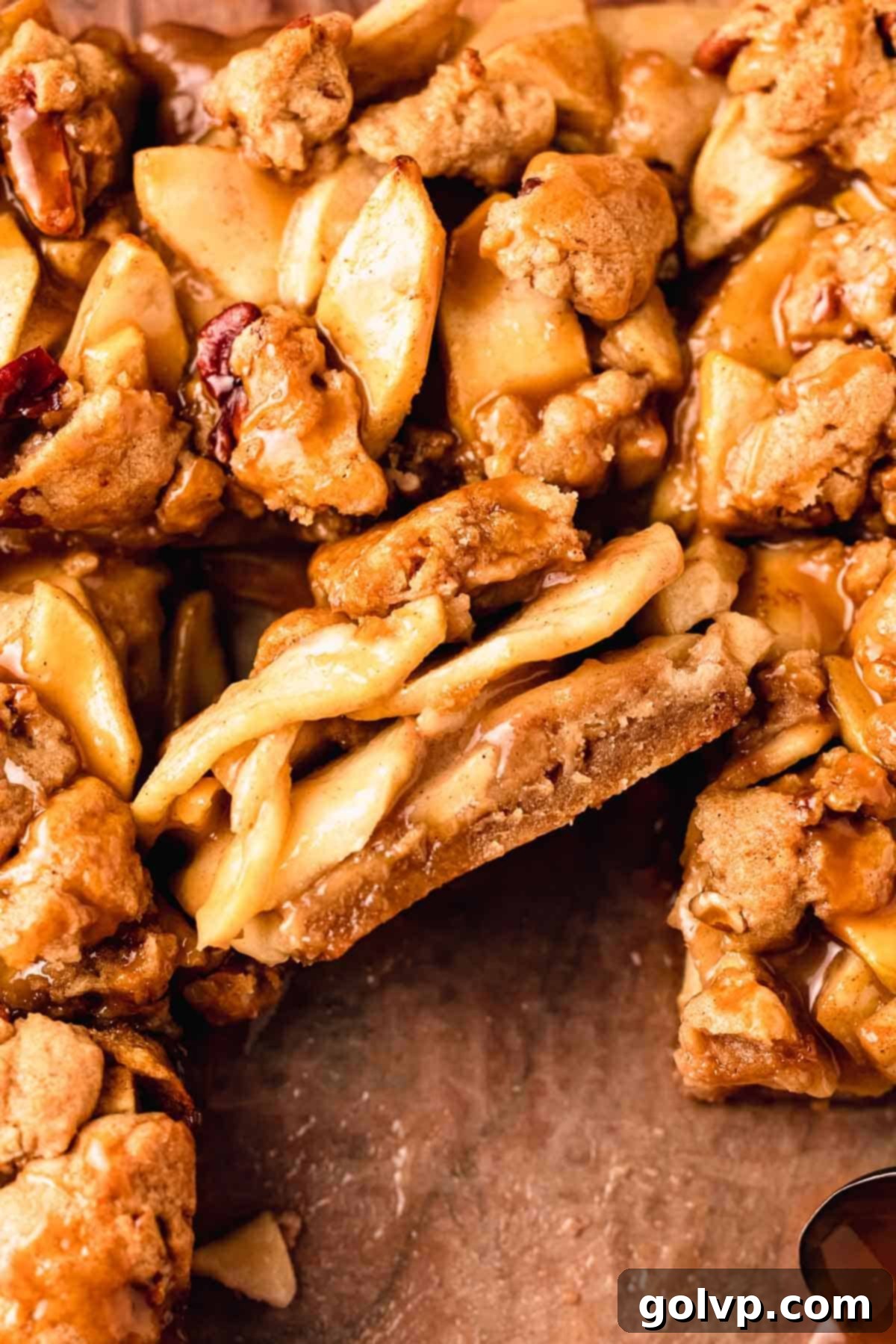 A perfectly sliced salted caramel apple pie bar on its side, revealing distinct layers of crisp shortbread, tender apple filling, and crumble topping.