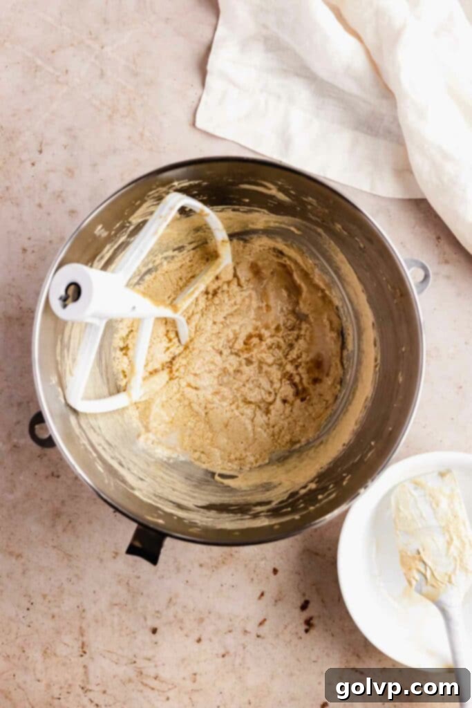 Mixing the wet ingredients for the maple cupcake batter in a large bowl, showing a well-combined, creamy texture.