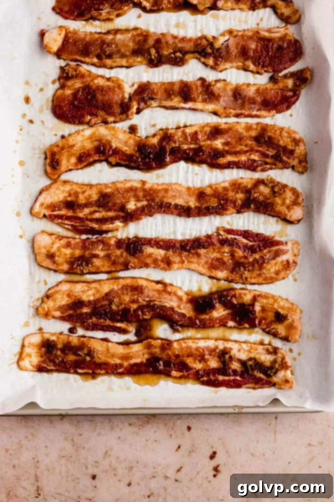 Bacon slices coated in brown sugar and maple syrup, arranged on a baking sheet, ready to be baked into candied perfection.
