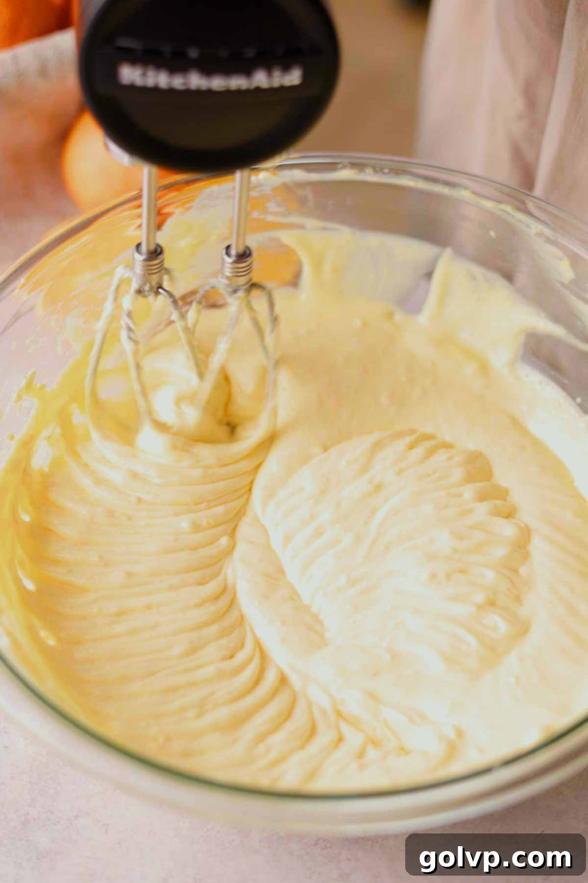 mixing orange cheesecake batter with electric mixer