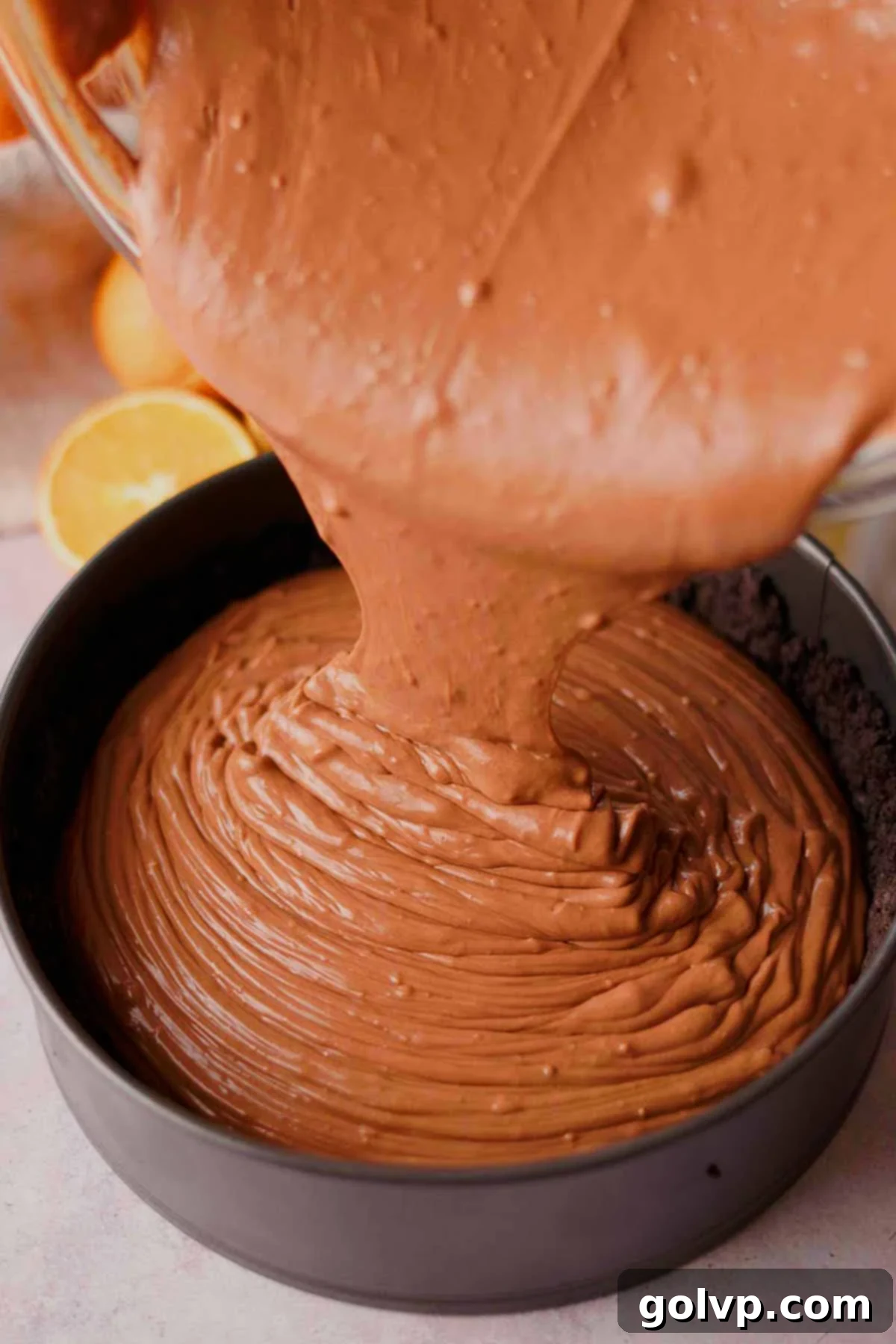 pouring chocolate orange cheesecake batter into chocolate crust