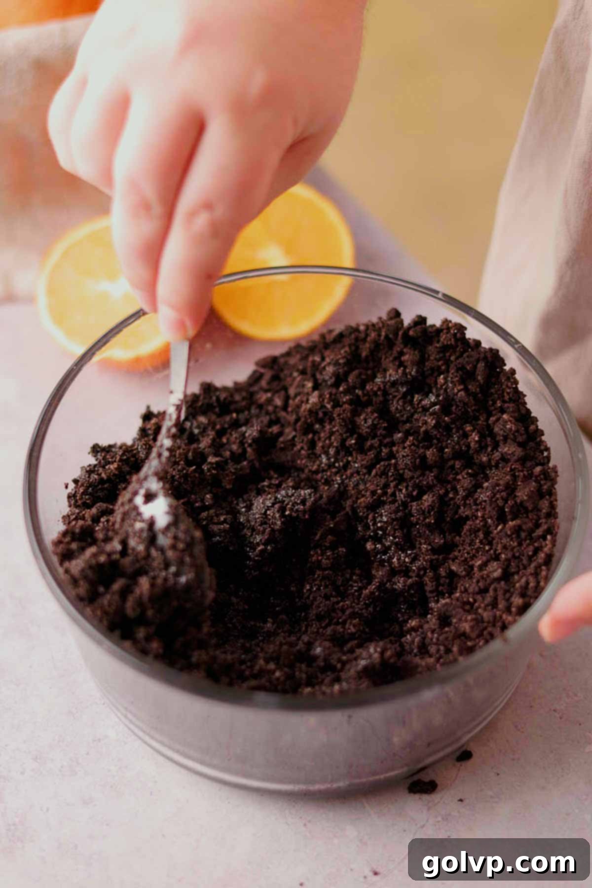 mixing chocolate cheesecake crust in clear glass bowl with spoon