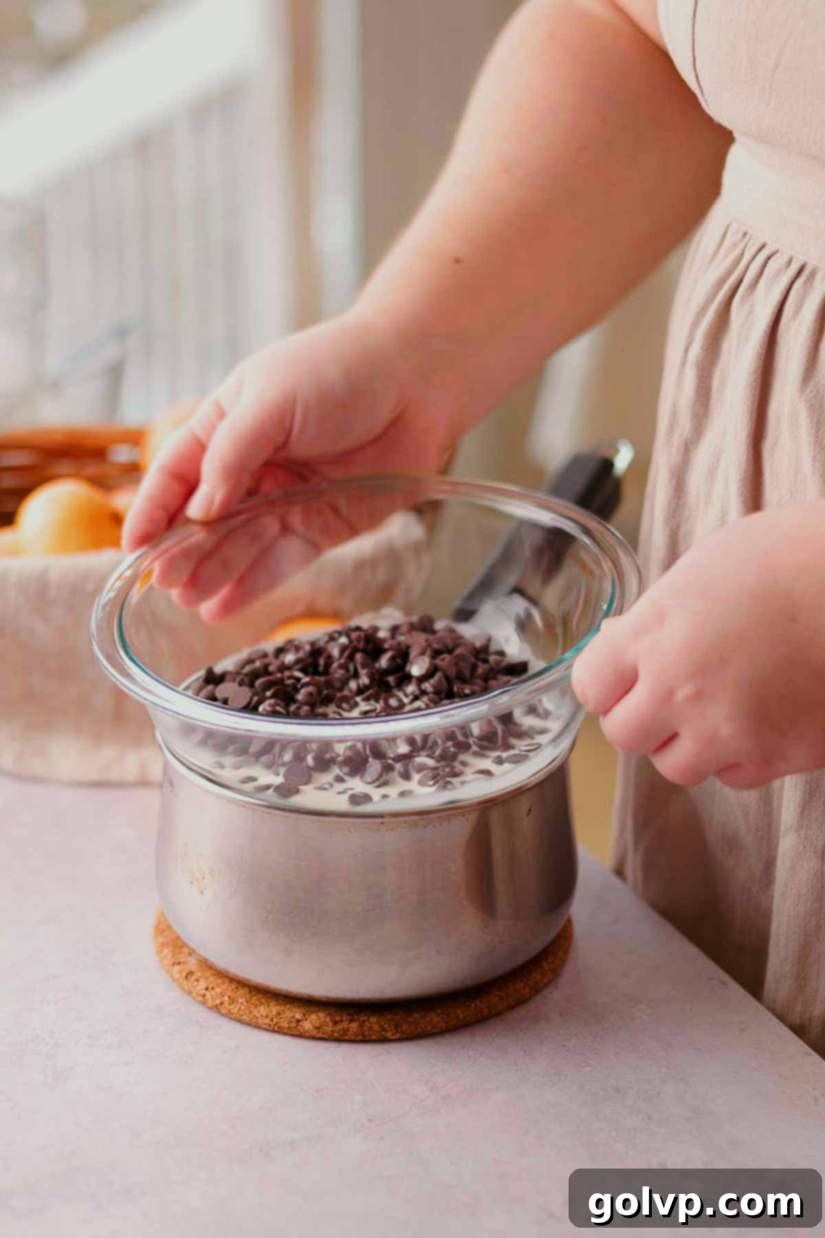 placing chocolate chips and cream in a bowl on top of a saucepan to melt