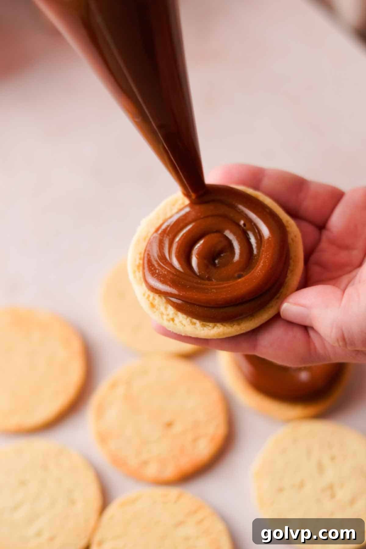 filling cookies with dulce de leche in a piping bag