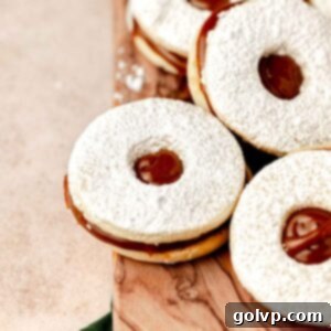 dulce de leche cookies dusted with powdered sugar on wooden cutting board