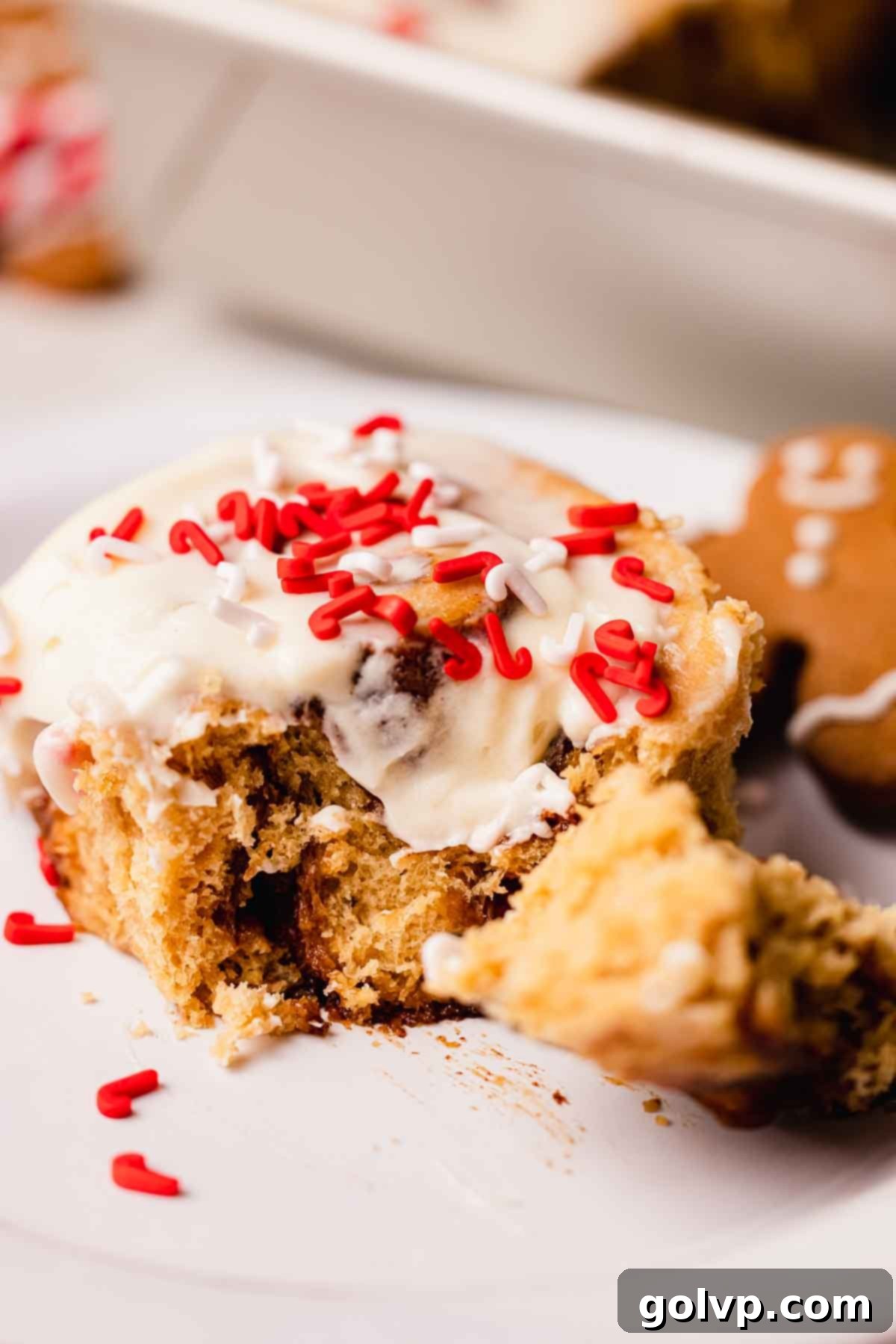 cinnamon roll on a plate with gingerbread filling, frosting, and sprinkles