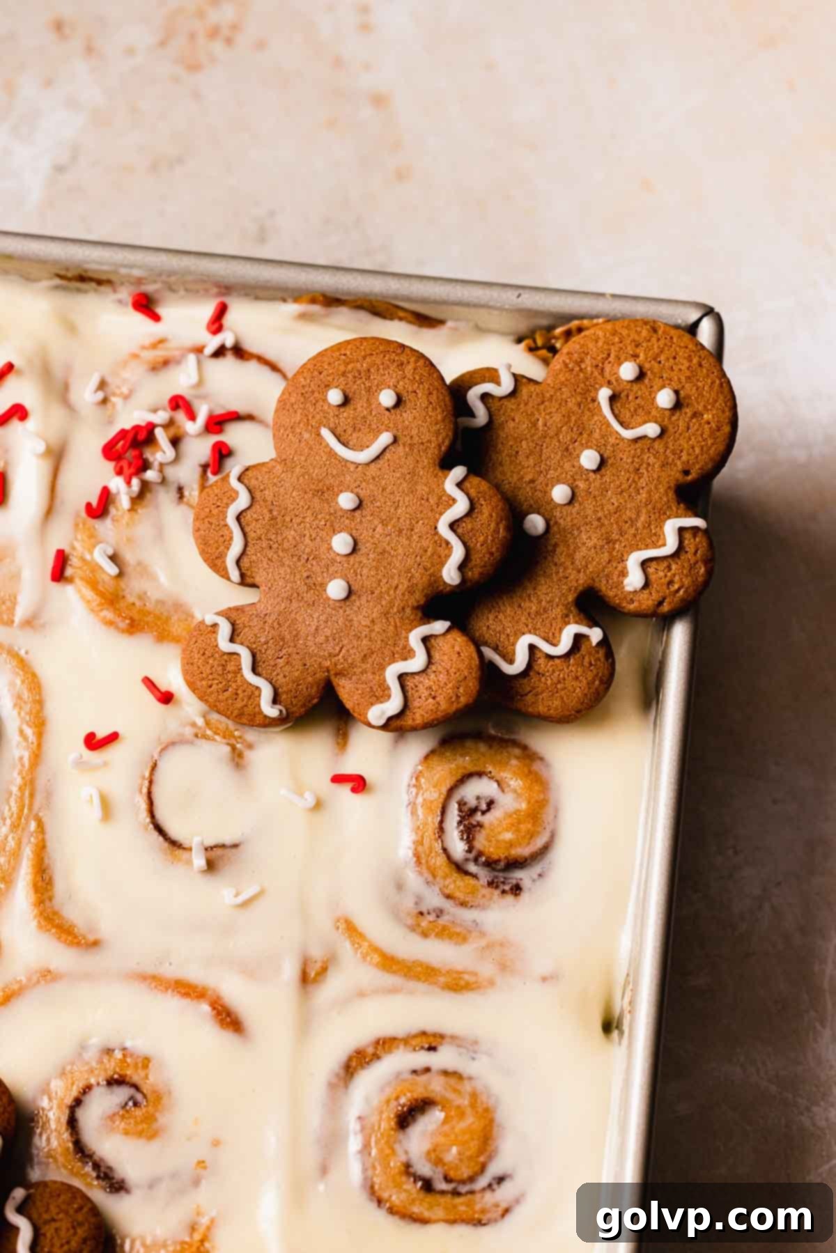 two gingerbread cookies on top of tray of gingerbread cinnamon rolls