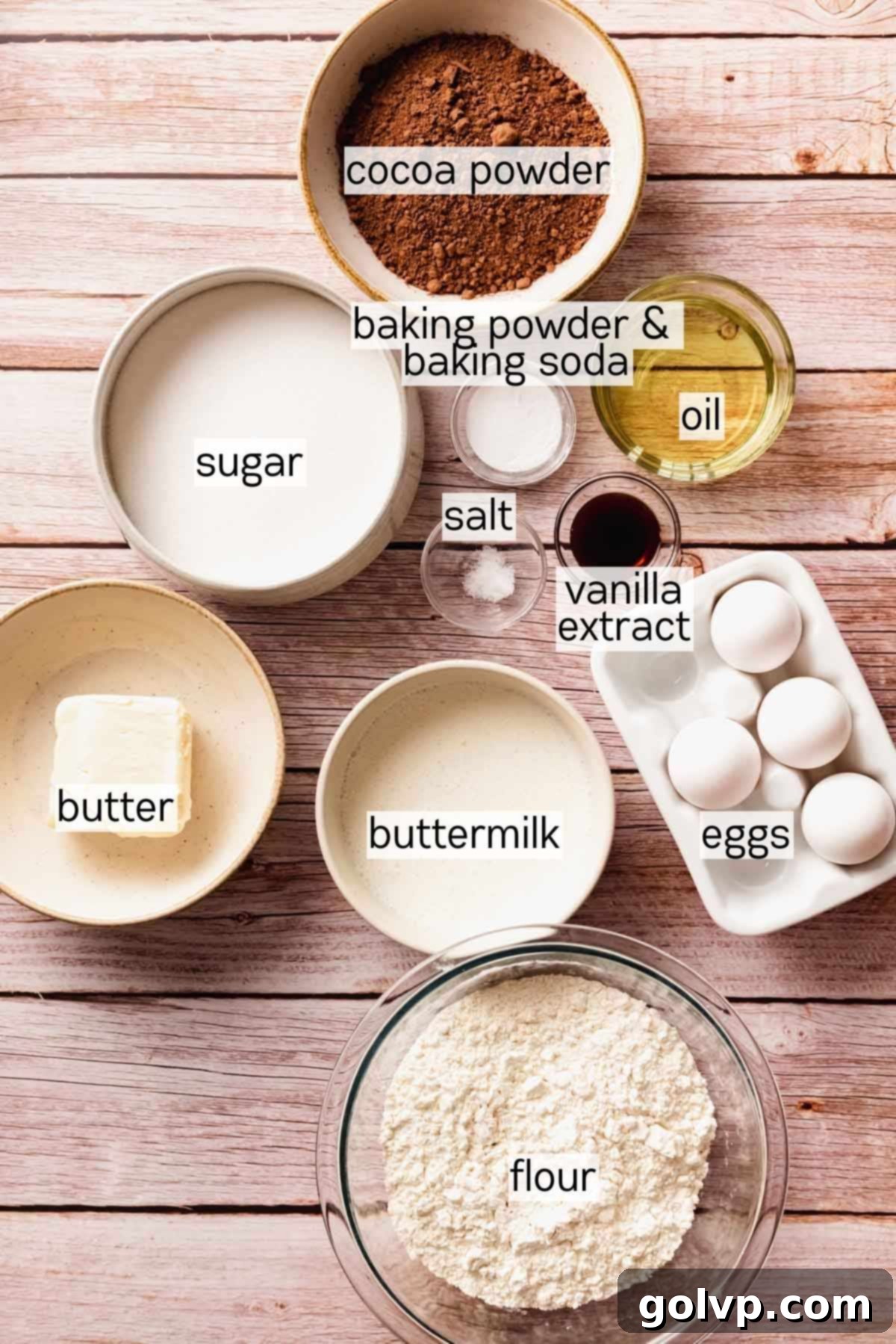 Individual bowls containing pre-measured ingredients for chocolate cake layers, ready for mixing.