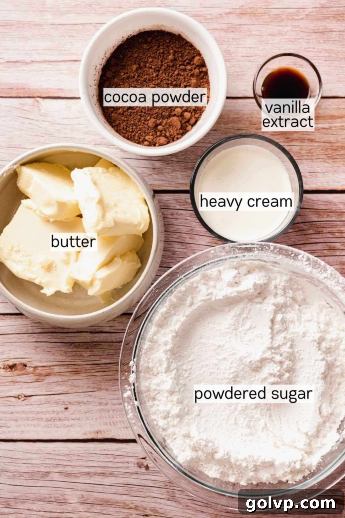 Ingredients for chocolate buttercream, including softened butter, powdered sugar, cocoa powder, and heavy cream, in bowls.