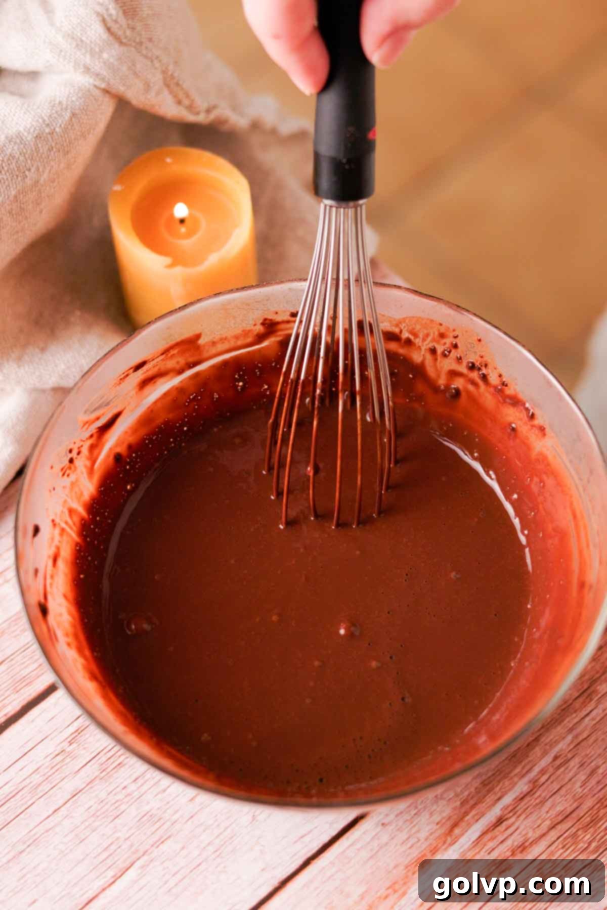 Whisking Dutch processed cocoa powder with boiling hot water in a glass bowl to bloom the cocoa and remove lumps.