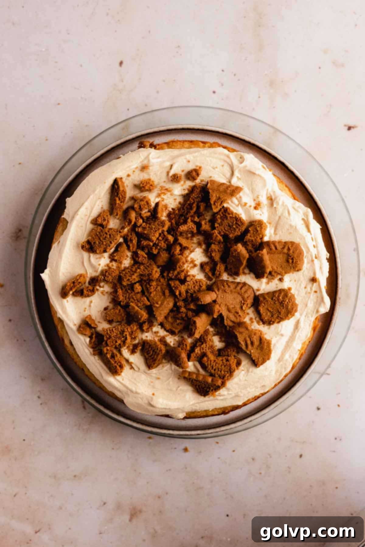 stacking biscoff cake with frosting and crushed cookies