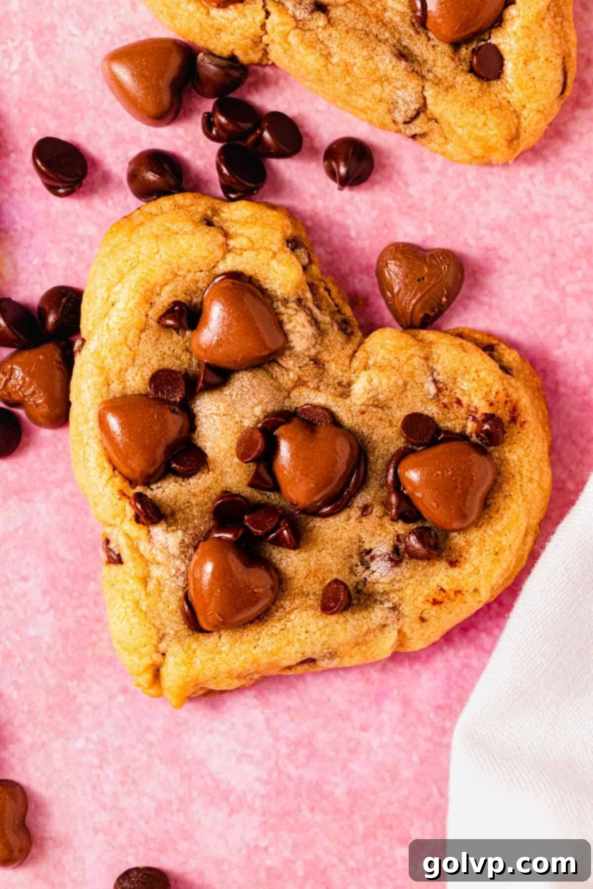 A beautifully arranged heart shaped chocolate chip cookie on a kitchen counter, surrounded by small chocolate hearts, inviting you to indulge.