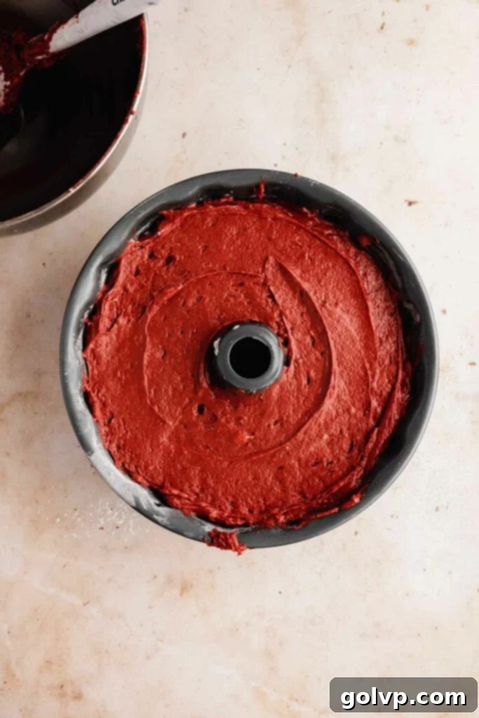 An unbaked red velvet bundt cake in the pan, showing the layers of batter and cream cheese swirl before baking.