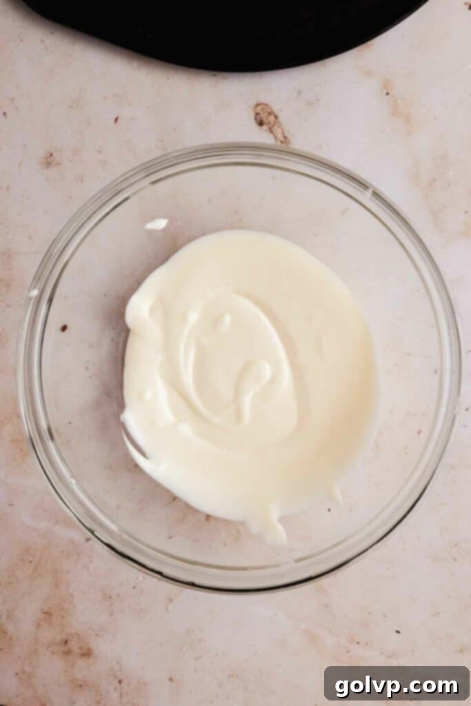 Image showing a bowl of perfectly smooth and creamy cream cheese glaze, ready to be poured over the bundt cake.