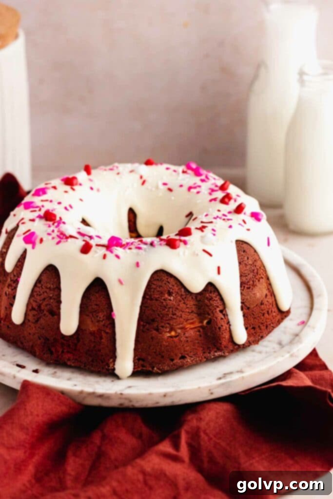 A beautifully glazed red velvet bundt cake adorned with colorful sprinkles, showcasing the final, festive presentation.