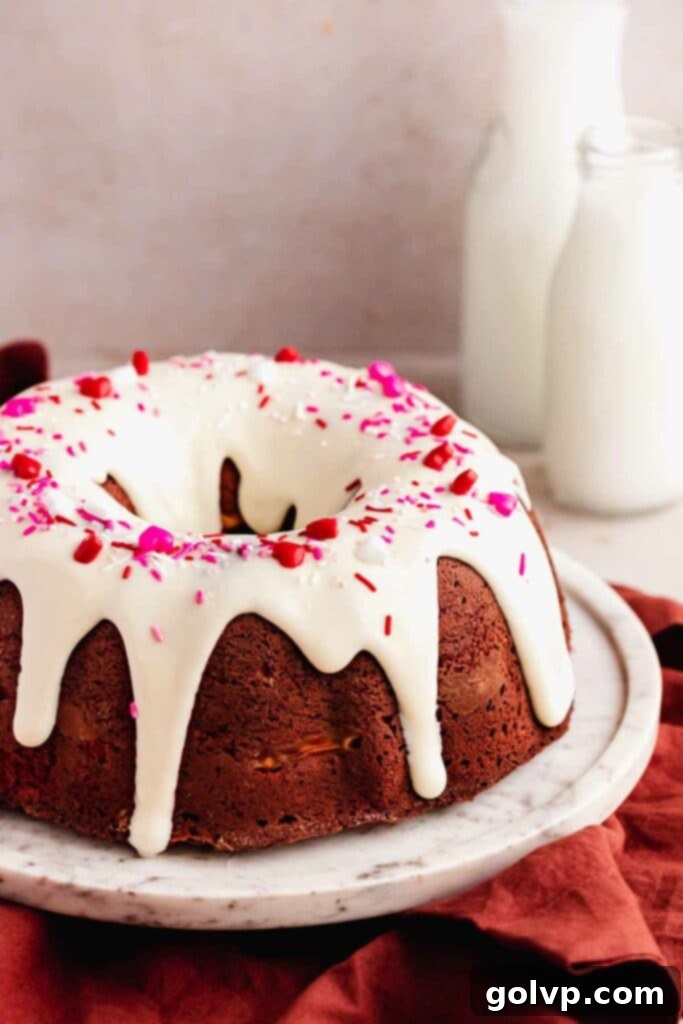 Decadent Red Velvet Bundt with Cream Cheese Swirl 3 Closeup of a red velvet bundt cake topped with a generous cream cheese glaze and colorful sprinkles, highlighting its vibrant red hue and creamy topping.