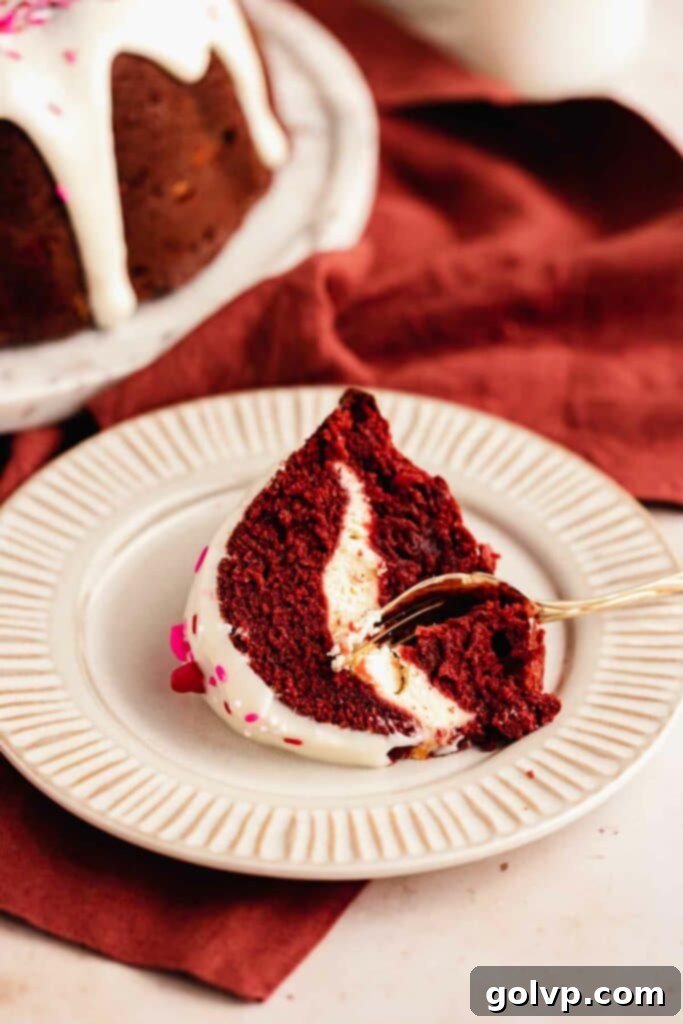 Decadent Red Velvet Bundt with Cream Cheese Swirl 4 A slice of red velvet bundt cake revealing its striking cream cheese filling swirl and moist, tender crumb texture.