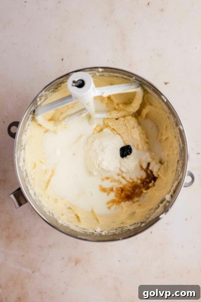 Picture of wet ingredients being added to the cake batter, showing the mixture becoming gloopy as dairy is incorporated.
