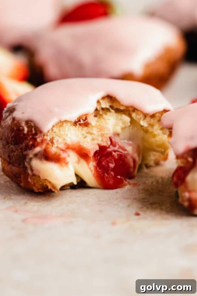 half of a strawberry filled donut with custard and strawberry