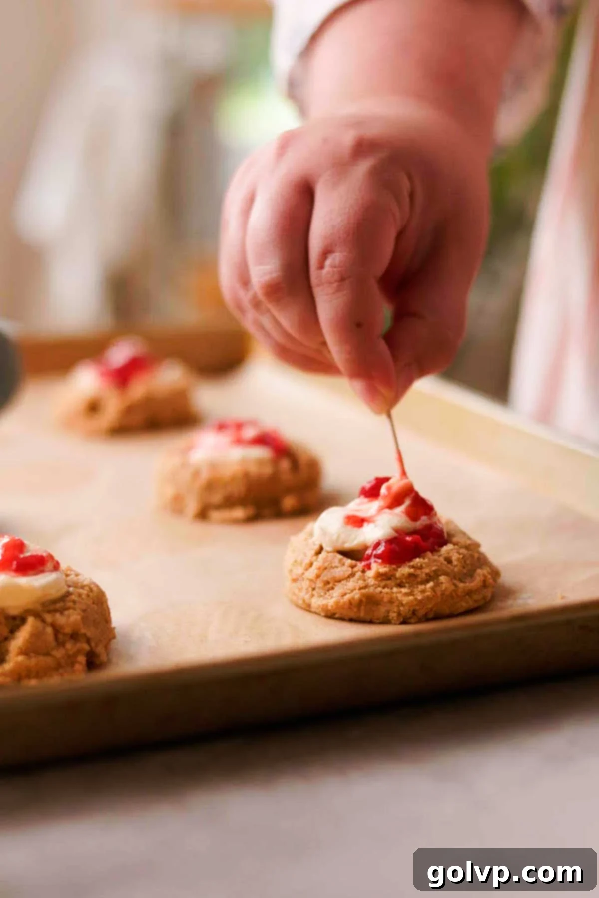 Decadent Strawberry Cheesecake Cookies 11 Swirling strawberry sauce and cheesecake filling together with a toothpick inside the cookie dough indent