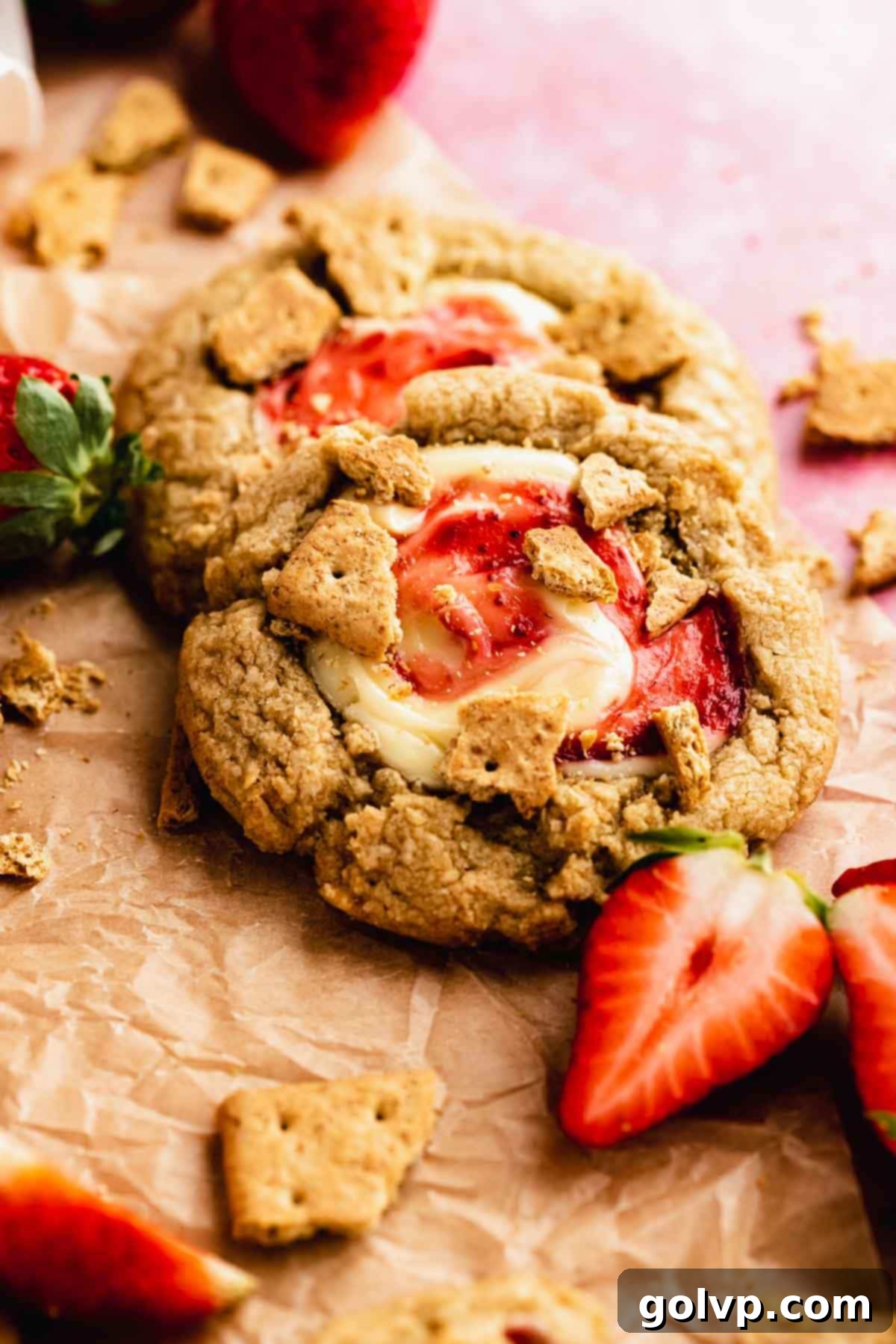 Close-up of a whole strawberry cheesecake cookie with a gooey middle and graham crumble.