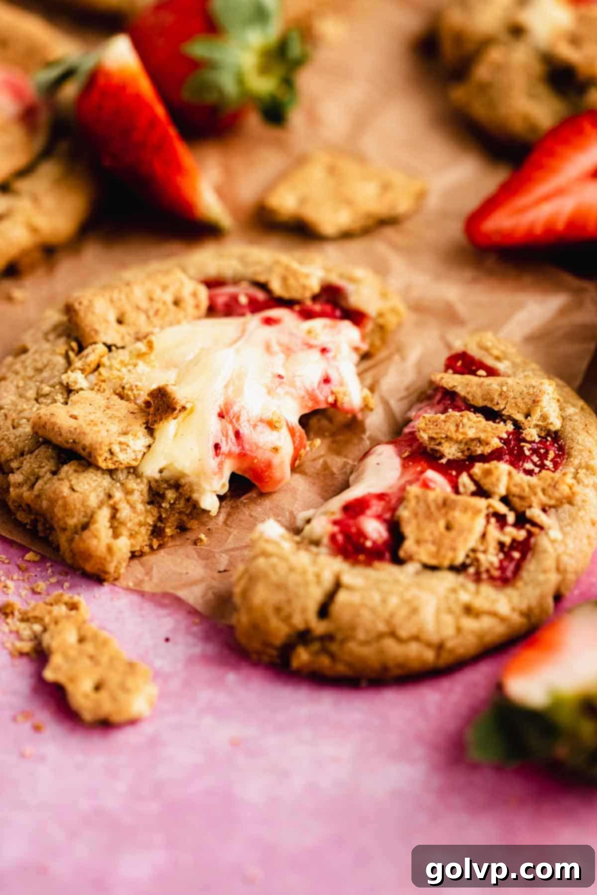A broken apart strawberry cheesecake cookie, showing the rich, creamy filling and cookie dough texture.