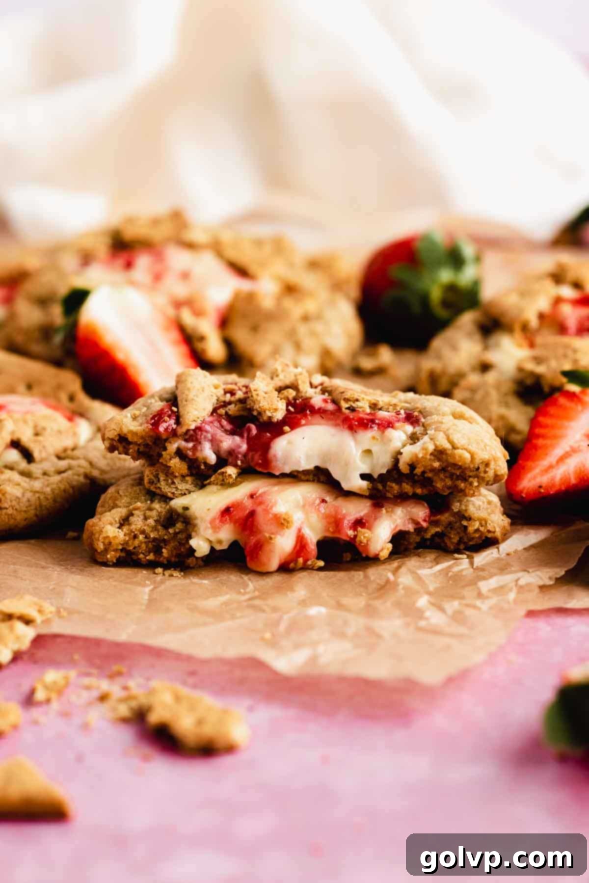 Strawberry cheesecake cookies broken in half to reveal the gooey filling and graham cracker swirl.