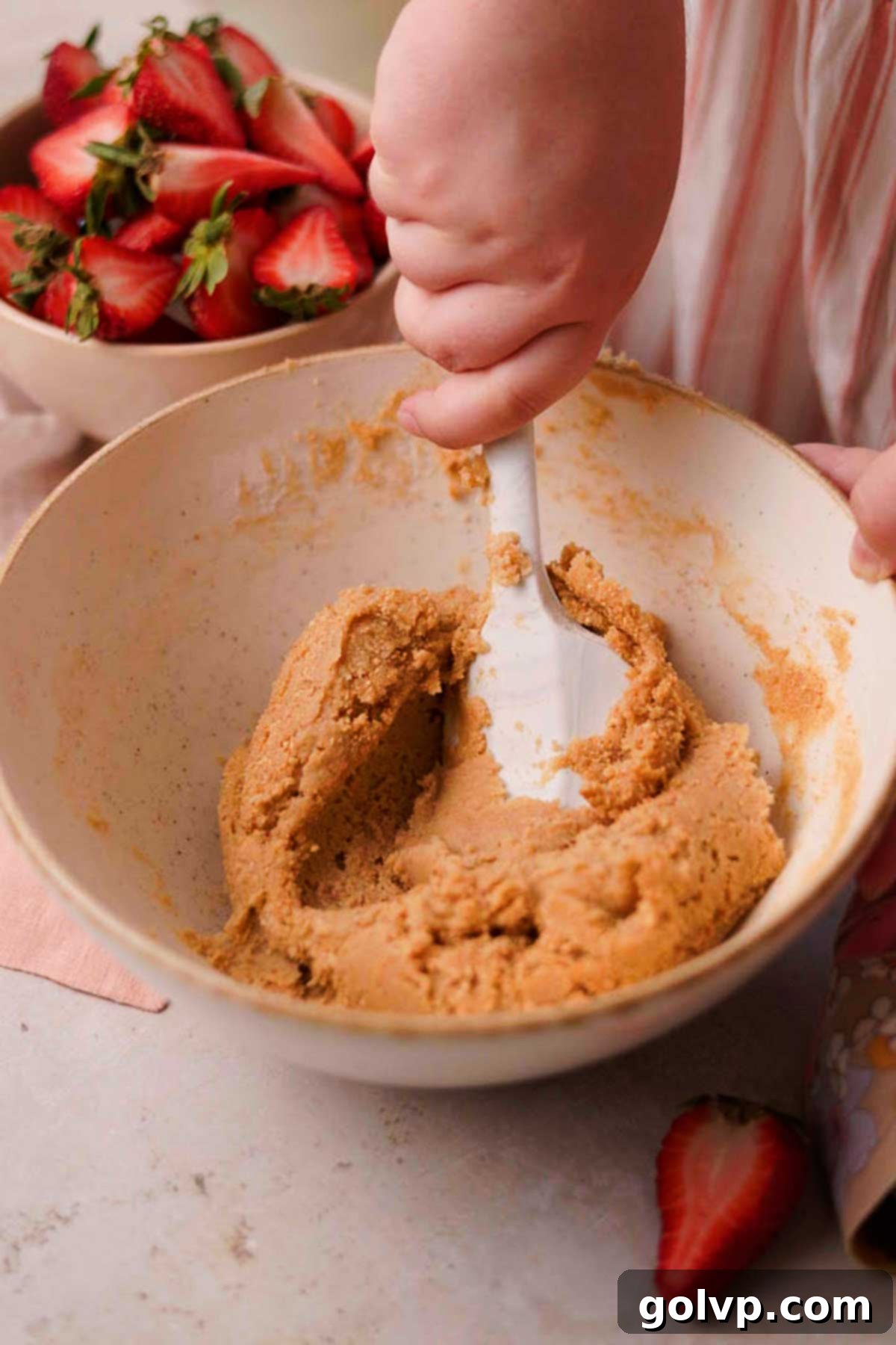 Gently folding graham cracker crumbs into the prepared cookie dough, creating a marbled effect.
