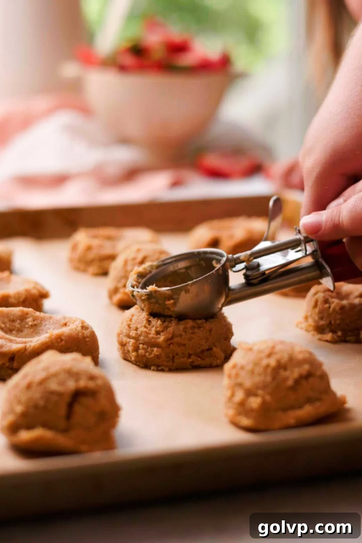 Decadent Strawberry Cheesecake Cookies 9 Scooping cookie dough balls onto a parchment-lined baking sheet and pressing an indent into each for the filling