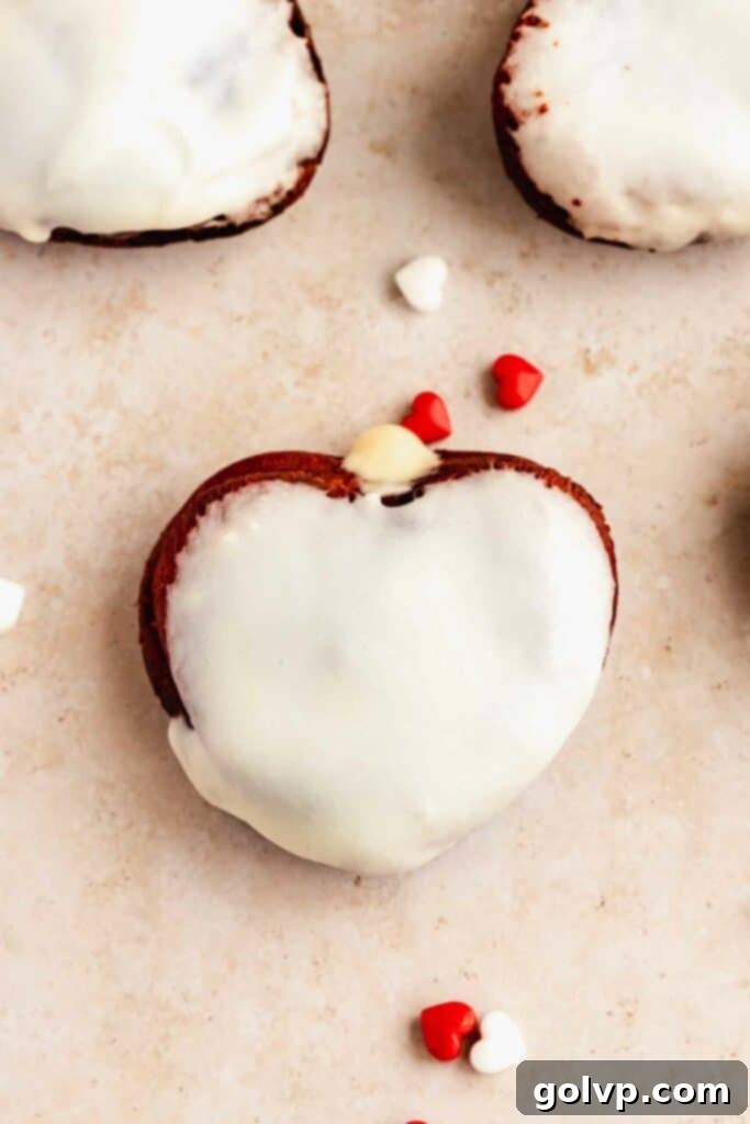 heart shaped red velvet glazed donut with a bite taken out, showing custard filling