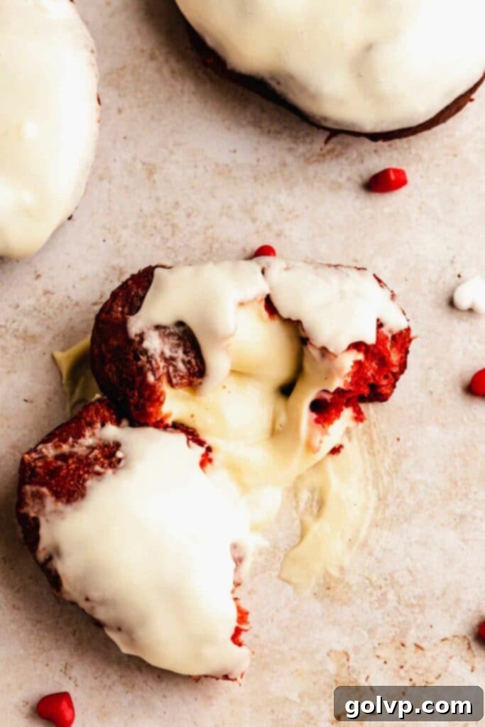 Torn apart red velvet donut with custard oozing out and cream cheese glaze