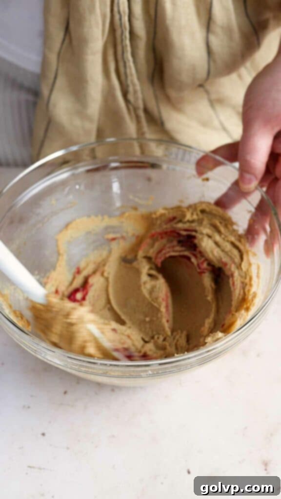 Adding red food colouring to creamed butter and sugar
