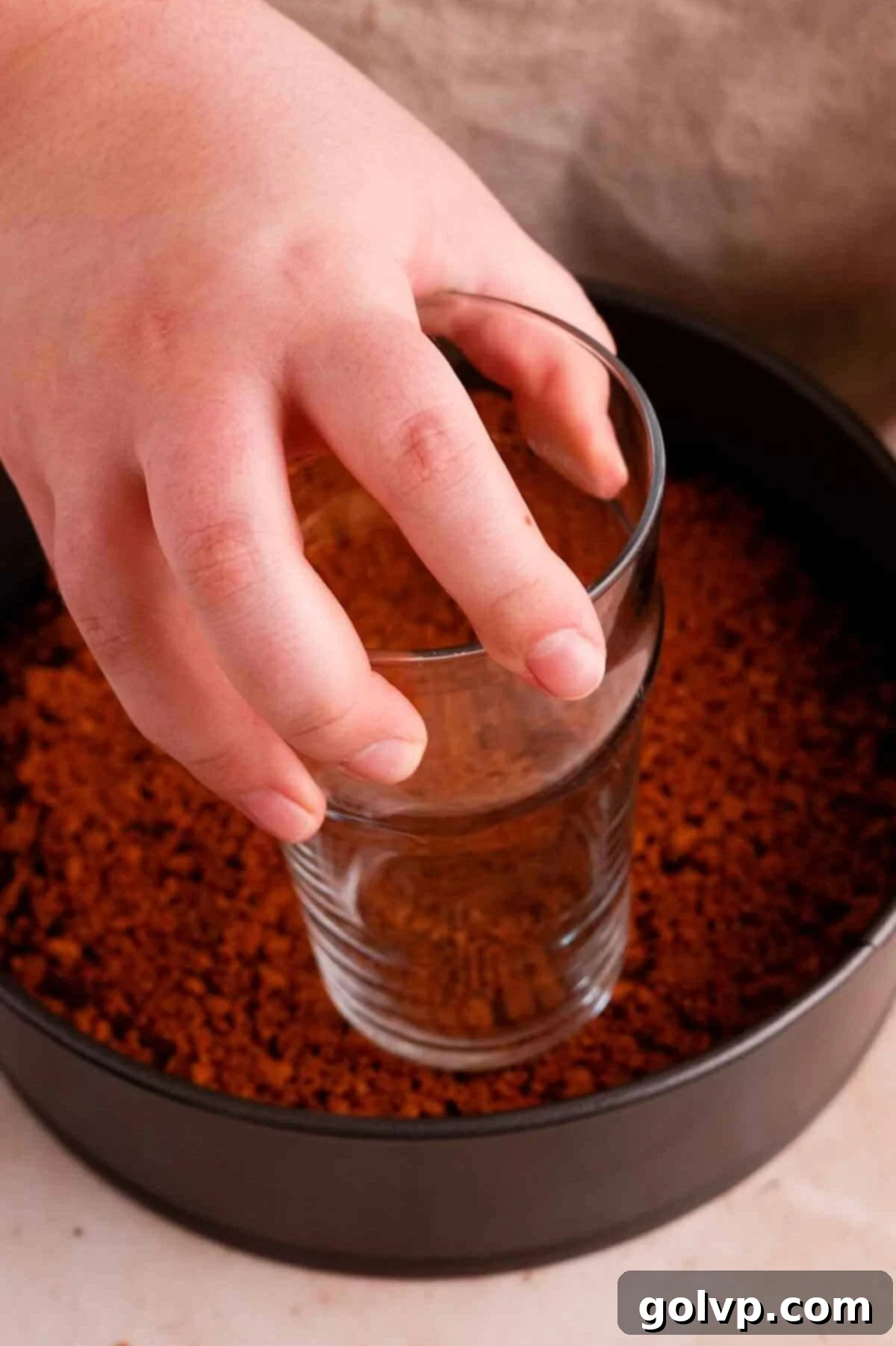 Firmly pressing the Biscoff cookie crust into the springform pan.
