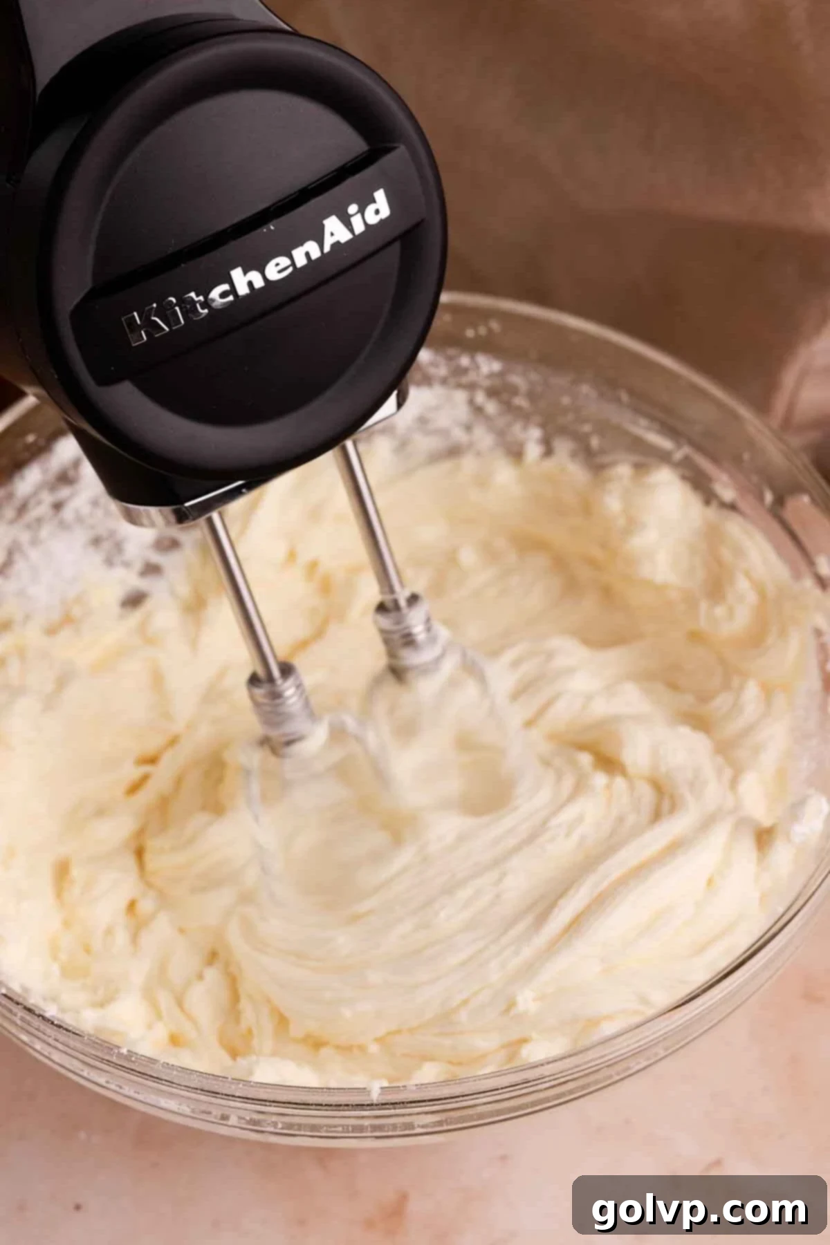 Beating cream cheese and powdered sugar until smooth and creamy for the cheesecake filling.