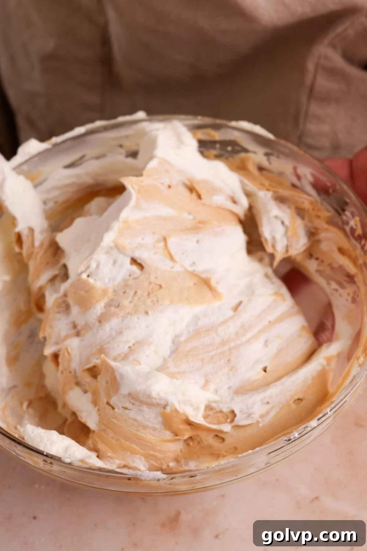 Gently folding in whipped cream into the Biscoff cheesecake mixture.