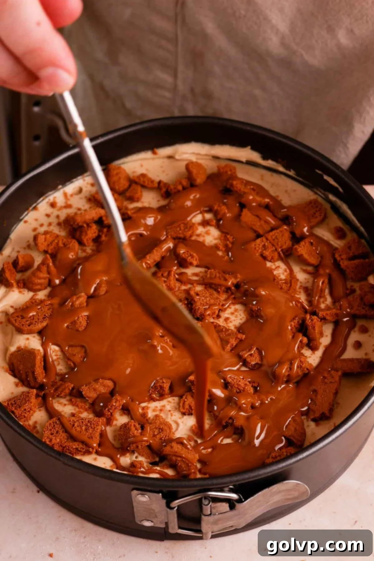 Creating a luscious middle layer with drizzled Biscoff spread and crushed cookies.