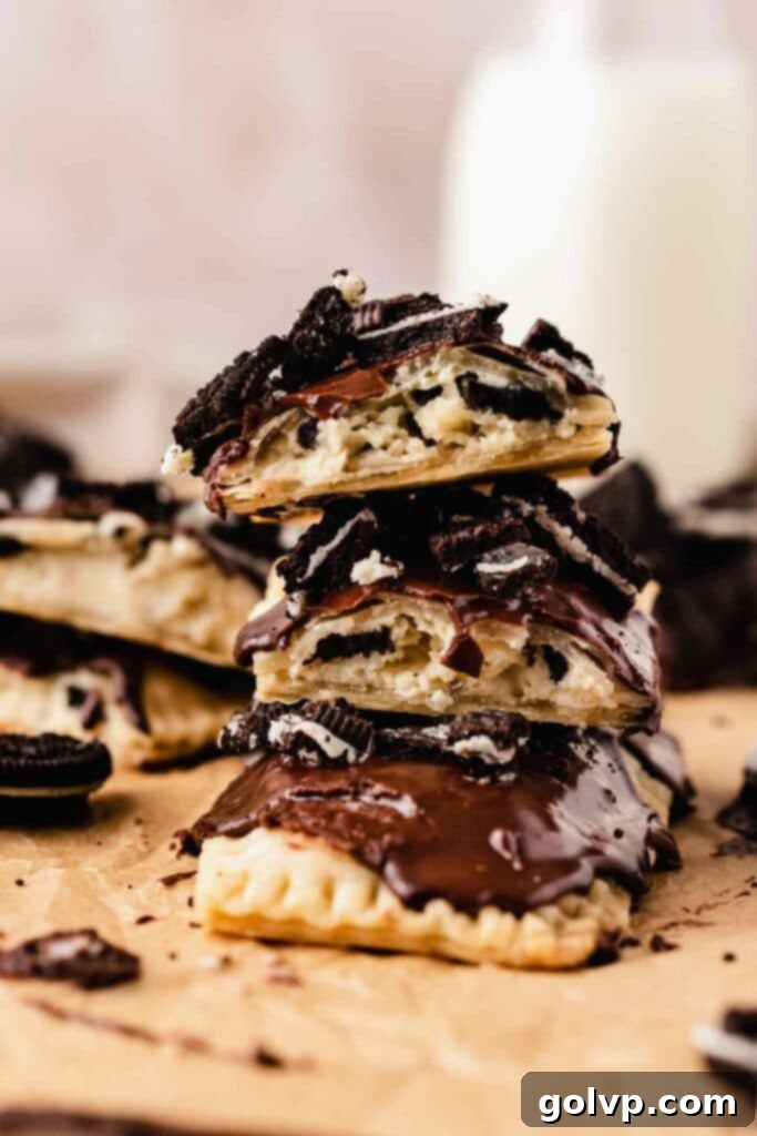 Stack of homemade Oreo Pop Tarts with flaky crusts, creamy filling, and chocolate glaze topped with crushed Oreos.