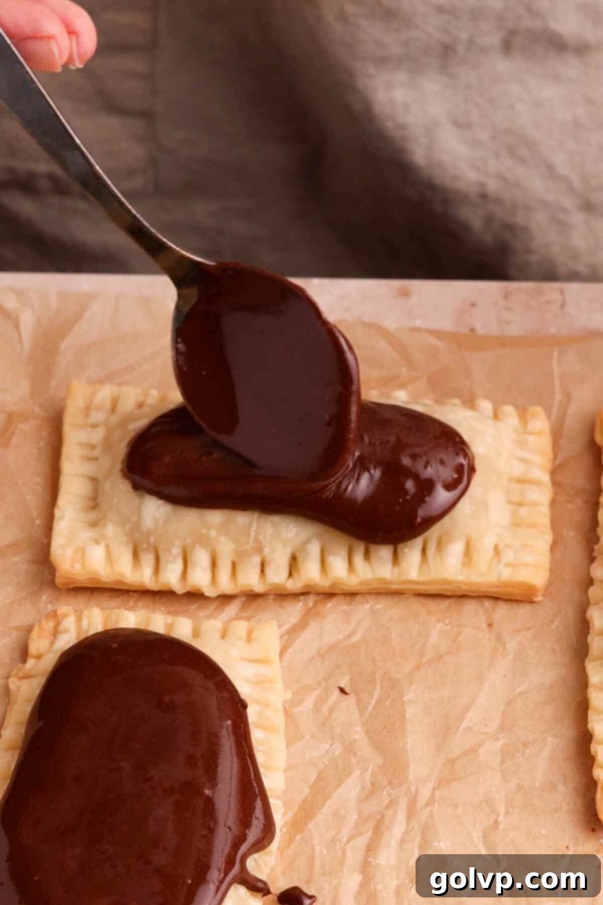 Topping warm Oreo Pop Tarts with a generous amount of thick chocolate glaze and crushed Oreo cookie pieces.