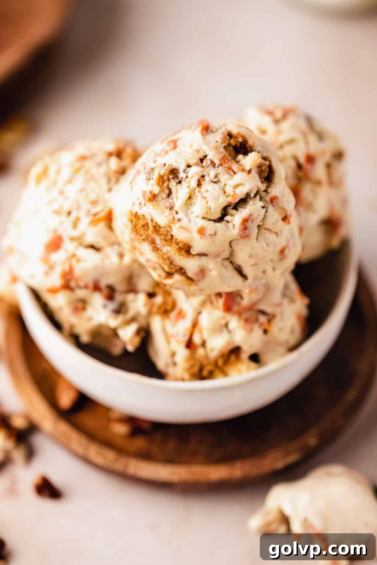 Spiced Carrot Cake Swirl 11 carrot cake ice cream in a white bowl with a spoon, decorated with cookie crumbs and nuts