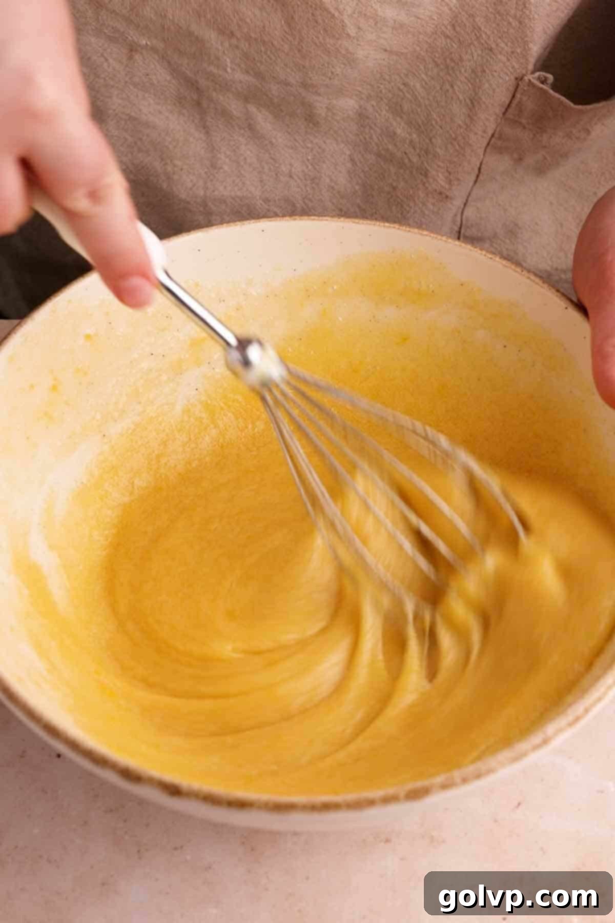 Whisked eggs, sugar, and salt in a bowl, showing a frothy and lightened texture.