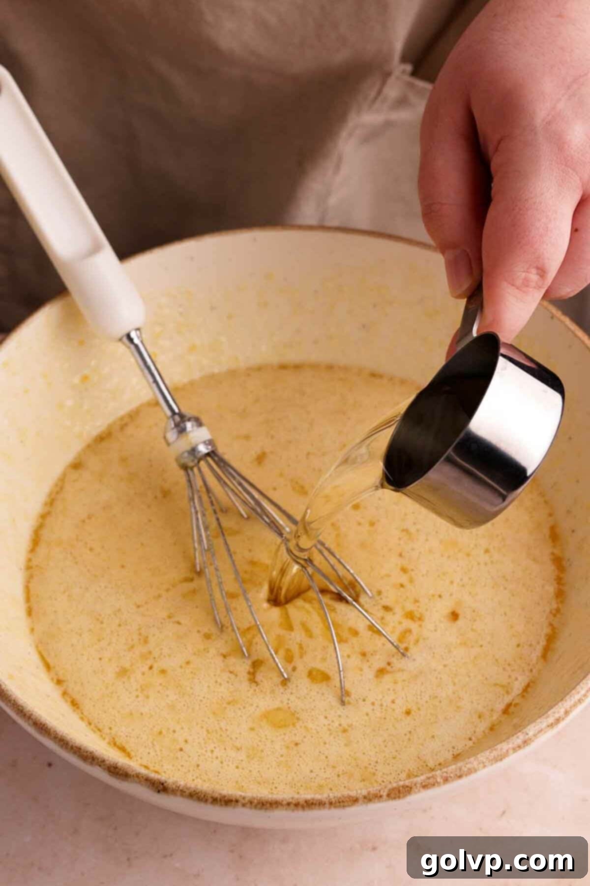Butter and oil being added to the chocolate bundt cake batter mixture in a bowl.