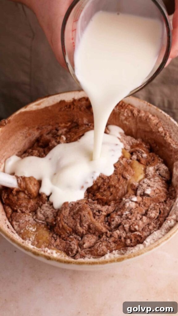 Pouring buttermilk into chocolate bundt cake batter.