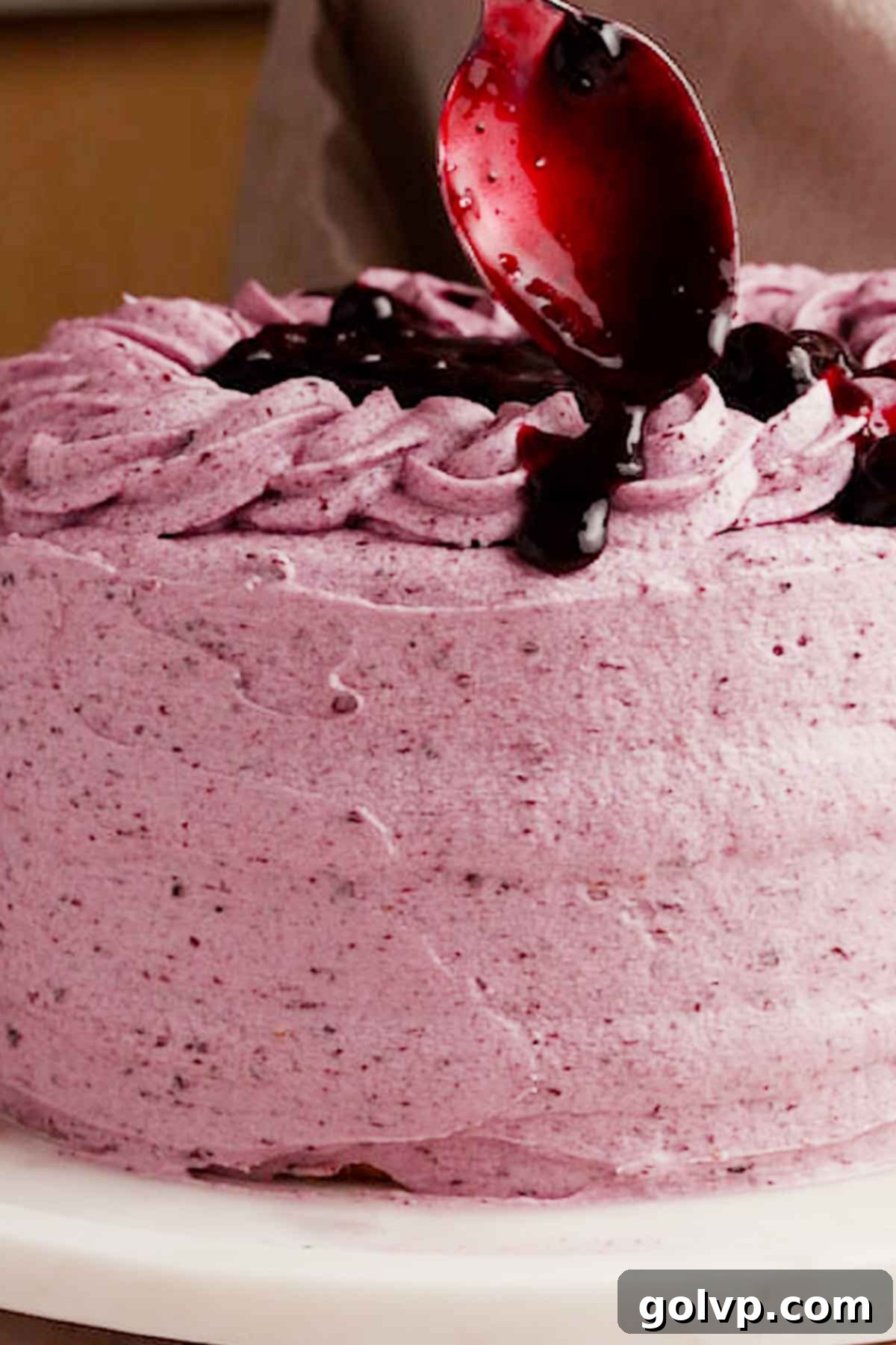 adding drips of blueberry filling on top of the cake